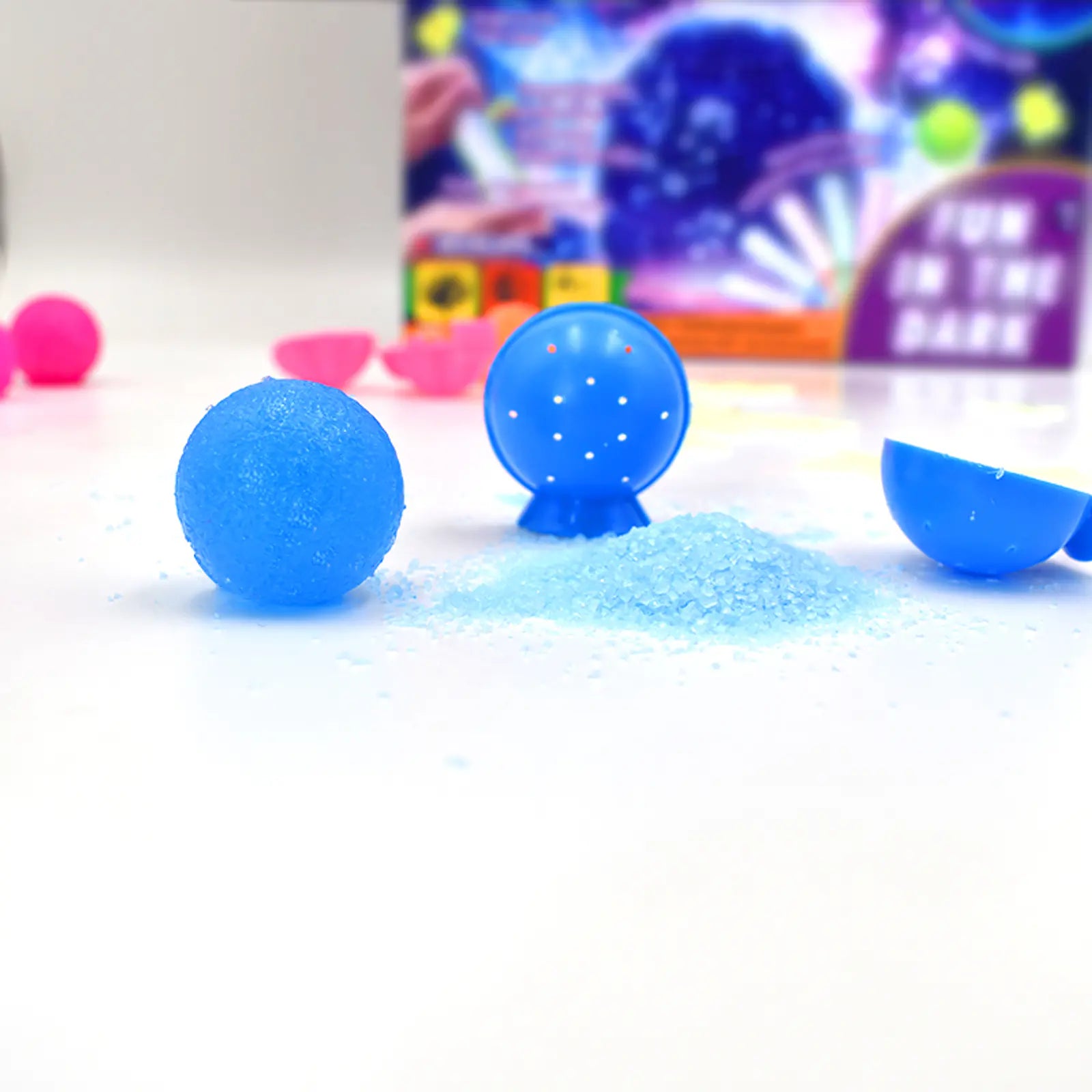 Blue slime balls with a star pattern on a white surface, with colorful packaging 