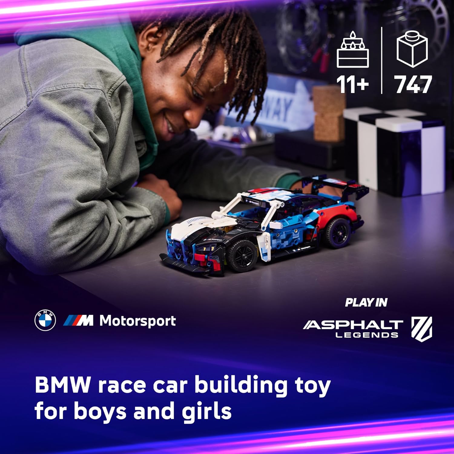 Child playing with a BMW race car building toy in a dark room with colorful lighting.