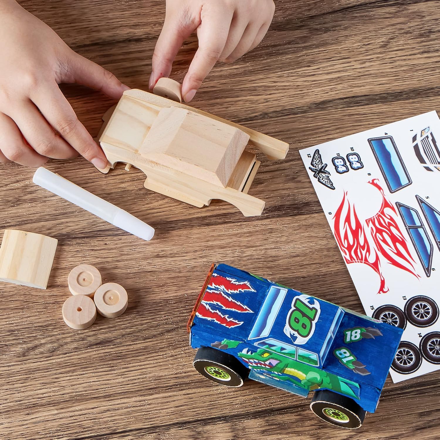 Children building a wooden toy car on a wooden table with a completed car and templates nearby.
